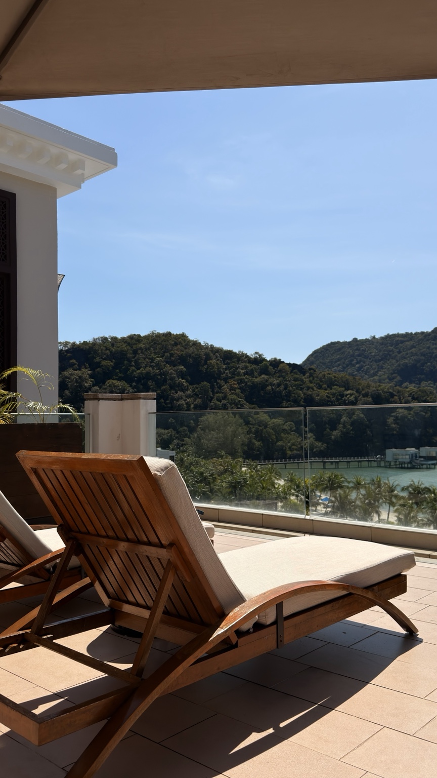 Wooden loungers on a balcony overlooking the sea and hills