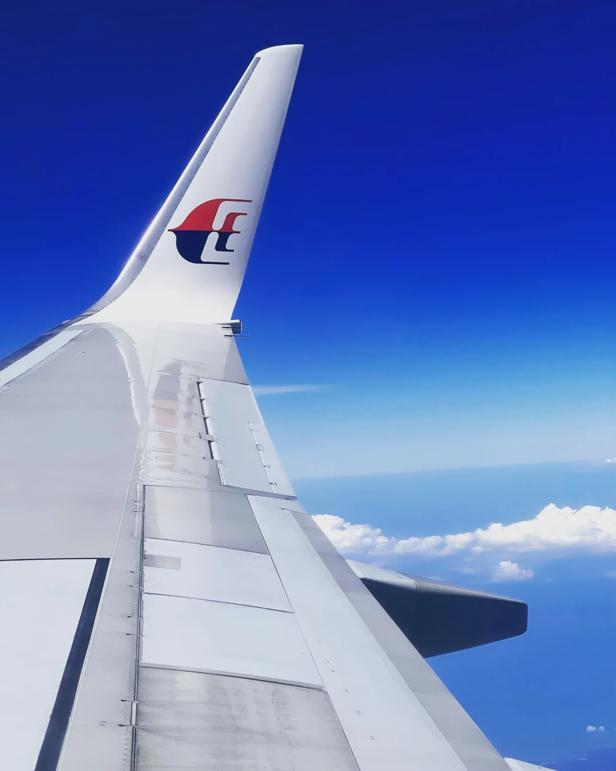 A Malaysia Airlines winglet above the clouds.